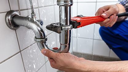 plumber fixing leaky pipe