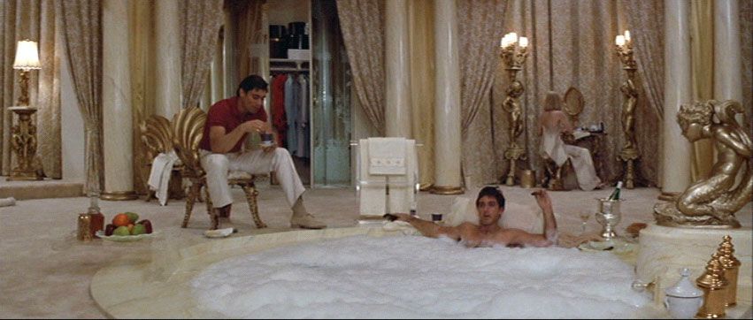 man lounging in luxe bubble bath with a man and woman around him