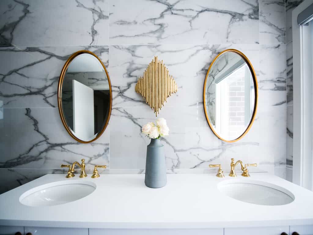 Bathroom counter with metal finishes on the mirrors and faucets.