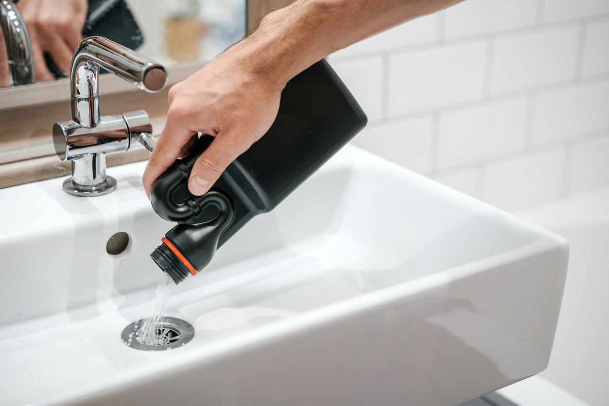 someone pouring chemical drain cleaner down a drain.